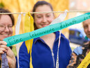 Foto: Drei Personen halten bunte Bänder mit handgeschriebenen Botschaften wie 'Eine lebenswerte Zukunft'. Die Bänder sind an einer Schnur befestigt und im Freien aufgenommen.