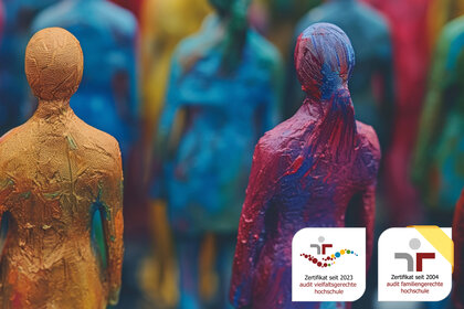 Foto: Bunte Figuren aus verschiedenen Materialien stehen dicht beieinander. Unten rechts sind zwei Zertifikate sichtbar: 'Zertifikat seit 2023 audit vielfaltsgerechte hochschule' und 'Zertifikat seit 2004 audit familiengerechte hochschule'.