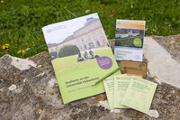 Foto: Verschiedene Broschüren und Flyer der Universität Hohenheim liegen auf einem Stein. Eine Broschüre zeigt das Schloss Hohenheim und trägt den Titel 'Studieren an der Universität Hohenheim'. Ein anderer Flyer ist ein 'Sustainable Campus Guide'.